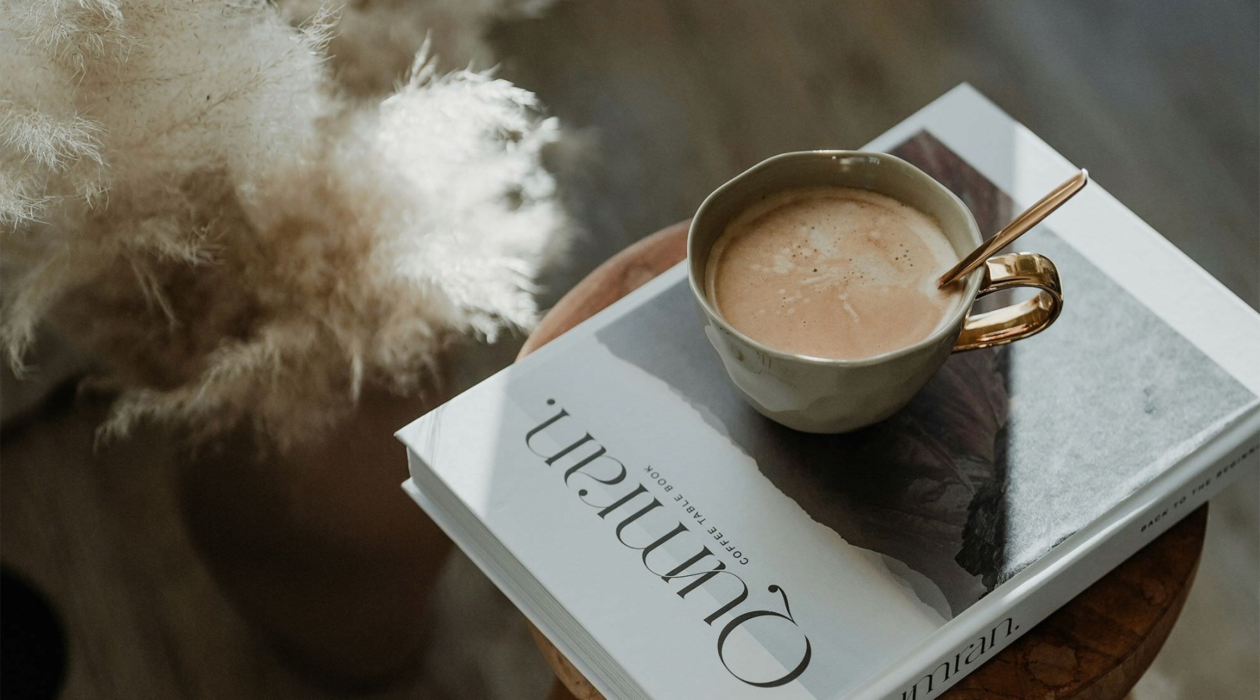 a cup of coffee on a book on a stool in a living room